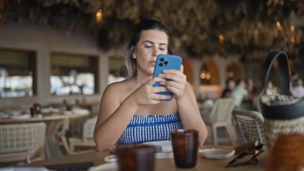 Νεαρή Ισπανόφωνη Γυναίκα Χαμογελά Ευτυχισμένη Χρησιμοποιώντας Smartphone Κάθεται Στο Τραπέζι — Αρχείο Βίντεο
