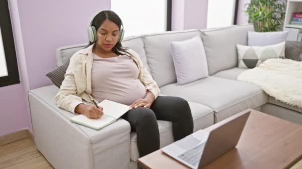 自宅で働く若いヒスパニック系女性を期待し ソファーに座り 母性文書を勉強し ビデオ通話で通話しながらメモを取る — ストック動画