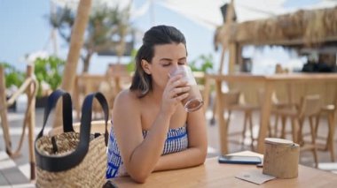 Genç İspanyol kadın güneşli restoran terasında buzlu kahve içiyor.