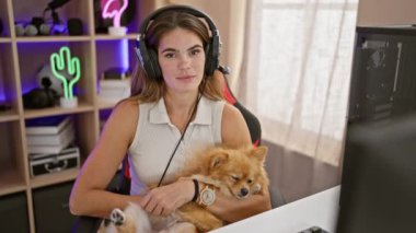 Gülümseyen, genç İspanyol kadın kulaklıklı, oyun dünyasına ustalıkla hükmediyor sevimli köpeğiyle oyun odasında, her gece siber oyuncular ordusu için yayın yapıyor..