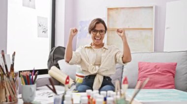 Heyecanlı genç İspanyol ressam zaferi kutluyor! Kanepede oturan güzel bir kadın, kolları muzaffer bir başarıyla kalkıyor, stüdyoda gururla bağırıyor..