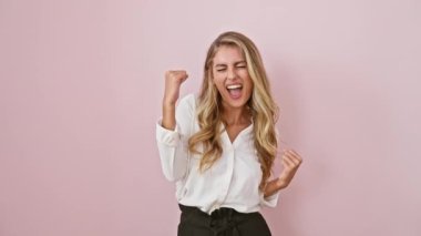 Gömlekli, kendinden emin sarışın kadın büyük zaferi kutluyor! Heyecanlı, güzel bir jest yapıyor, pembe arka planda sevinç çığlıkları atıyor..