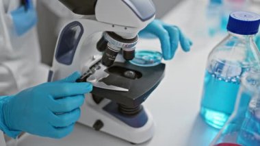 Genç İspanyol bilim adamı laboratuvarda mikroskopla örnek arıyor.