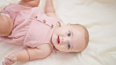 Sevimli küçük bebek, rahatlamış ve rahat, kanepeye uzanmış, battaniyeye gülümsüyor, yeni doğmuş huzurlu bir yaşam tarzının mükemmel bir resmi..