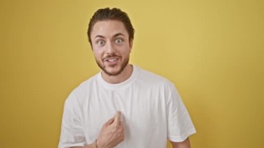 Genç İspanyol adam kendini izole edilmiş sarı arka planda kutlama yaparken gösteriyor.