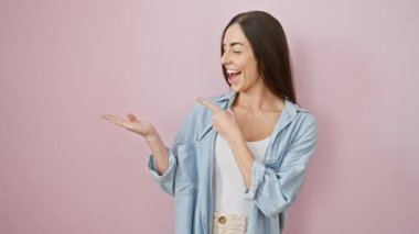 Göz kamaştırıcı İspanyol kadın günlük kıyafetlerle poz veriyor! Sevinçten havalara uçuyor ve büyüleyici bir gülümseme sergiliyor! Canlı pembe bir arka planda izole edilmiş..