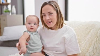 Anne, kızıyla kanepede oturuyor ve evde video görüşmesi yapıyor.