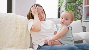 Stresli bir anne evdeki kanepede oturuyor, günlük yaşam tarzının ortasında kızıyla yüzleşiyor.