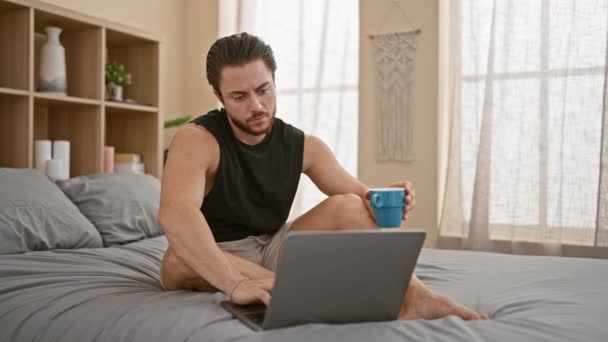Young Hispanic Man Using Laptop Drinking Coffee Bedroom — Stok video