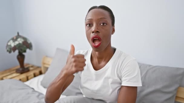 ベッドルームの驚くべきアフリカ系アメリカ人女性 驚くような表情でベッドに横たわり 口が広く開いています — ストック動画