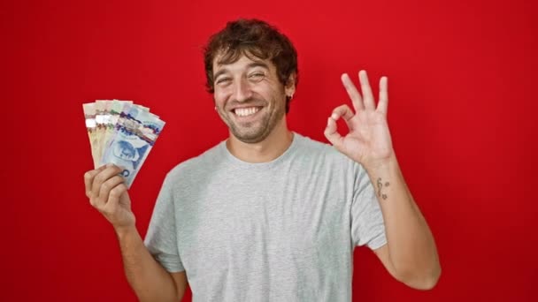 Veselý Mladý Muž Držící Kanadské Dolarové Bankovky Gestikuluje Červeném Izolovaném — Stock video