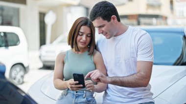 Güzel bir çift caddede duran akıllı telefonu kullanıyor.