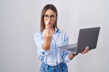 Young woman working using computer laptop showing middle finger, impolite and rude fuck off expression 