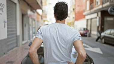 Genç İspanyol adam caddede geri geri duruyor.