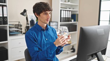 Genç İspanyol iş adamı ofiste dolar sayarken görüntülü arama yapıyor.