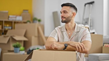 Genç İspanyol adam yeni evindeki karton kutuya yaslanıyor.
