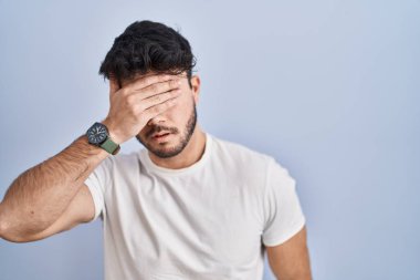 Beyaz arka planda sakallı İspanyol bir adam elleriyle gözlerini kapatıyor, ciddi ve üzgün görünüyor. Görme, saklama ve reddetme konsepti 