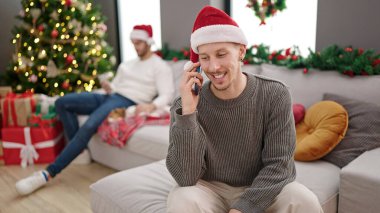 Noel 'i kutlayan iki erkek evde akıllı telefondan konuşuyor.