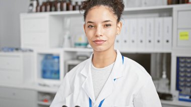 Ciddi yüzlü, genç ve güzel İspanyol kadın bilim adamı. Laboratuvarında sıkı çalışıyor. Mikroskopla profesyonel bir güven yayıyor..