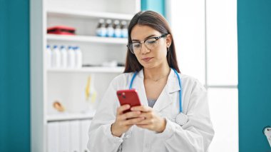 Klinikte akıllı telefon kullanan genç, güzel İspanyol kadın doktor.