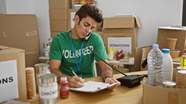 Genç İspanyol gönüllü yardım derneğindeki panoda telefonla konuşuyor.