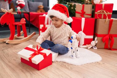 Sevimli İspanyol çocuk evde Noel ağacının yanında yerde oturan oyuncak kutusunu açıyor.