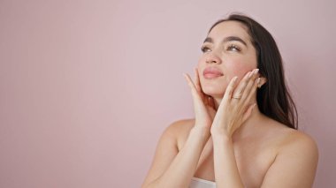 İzole edilmiş pembe arka planda masaj yapan güzel İspanyol bir kadın.