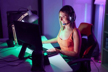 Young beautiful hispanic woman streamer playing video game using computer at gaming room
