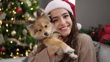 Köpeğiyle gülümseyen genç İspanyol kadın Noel 'i evde kutluyor.