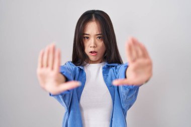 Beyaz arka planda duran genç Çinli kadın avuçlarıyla jesti durduruyor, kızgın ve hayal kırıklığına uğramış ifade ediyor. 