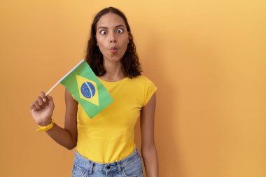 Brezilya bayrağı tutan genç İspanyol kadın dudaklarıyla balık suratı yapıyor, çılgınca ve komik bir jest. Komik ifade. 