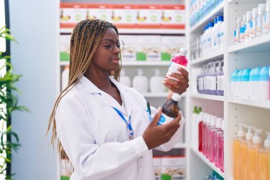 Eczanede ilaç şişeleri tutan Afrikalı Amerikalı kadın eczacı.