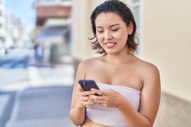 Sokakta akıllı telefon kullanan, kendine güvenen genç İspanyol kadın.