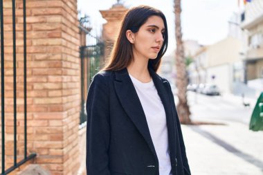 Young beautiful hispanic woman looking to the side with serious expression at street