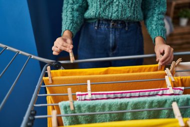 Genç ve güzel İspanyol kadın çamaşırhanede çamaşır ipine elbise asıyor.