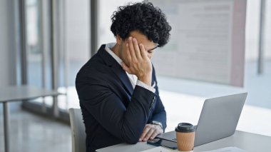 Genç Latin iş adamı ofiste dizüstü bilgisayar kullanıyor.