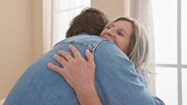 Kendine güvenen anne ve oğul, mutlu evlerinde sevgi dolu, gündelik hayatlarının tadını çıkararak, evde sıcak, gülümseyen bir kucaklaşmayı paylaşıyor..