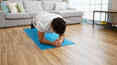 Genç latin adam evde vücut egzersizi yapıyor.