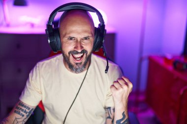 Genç kel adam oyun odasında video oyunu oynuyor. Kazanan yüz ifadesiyle.