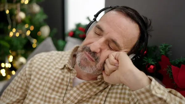 Mężczyzna Średnim Wieku Słuchający Muzyki Śpiącej Kanapie Przy Choince Domu — Zdjęcie stockowe
