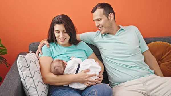 Family of three bonding and breastfeeding sitting on the sofa at home