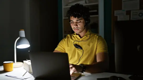 Young latin man business worker using laptop and headphones working at the office