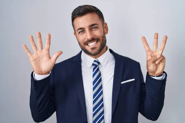 ハンサムなヒスパニックの男性は 自信と幸せに微笑んでいる間 スーツとネクタイを示し 指番号8を指で指摘しています — ストック写真