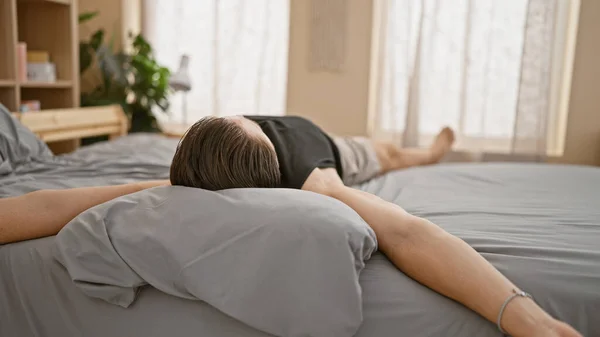 寝室で腕を伸ばすベッドに横たわる若いヒスパニックの男 — ストック写真
