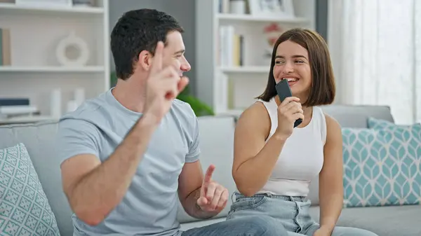 Beautiful couple singing song using tv remote control as a microphone dancing at home