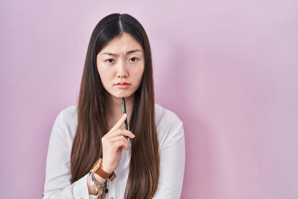 Kinesisk Ung Kvinna Håller Penna Över Rosa Bakgrund Deprimerad Och — Stockfoto