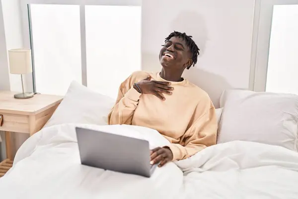 African american man having video call sitting on sofa at bedroom