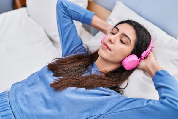 Stock image Young beautiful hispanic woman listening to music lying on bed at bedroom