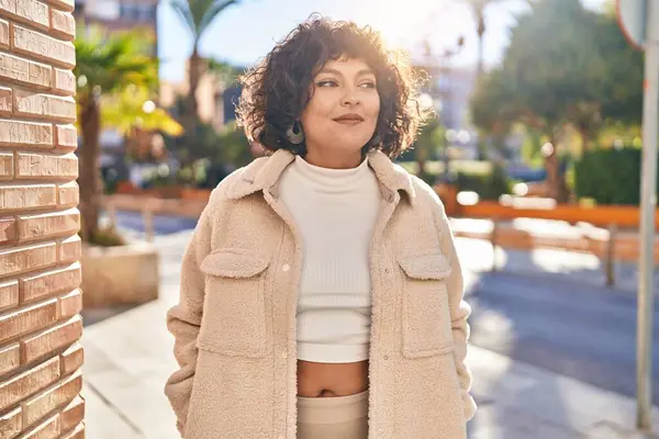 Young beautiful hispanic woman smiling confident looking to the side at street