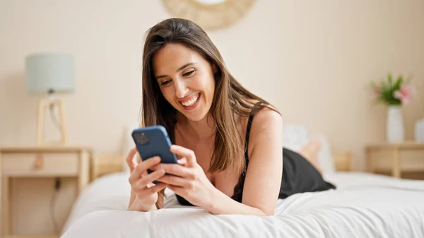 Νεαρή Όμορφη Ισπανόφωνη Γυναίκα Που Χρησιμοποιεί Smartphone Ξαπλωμένη Στο Κρεβάτι — Φωτογραφία Αρχείου